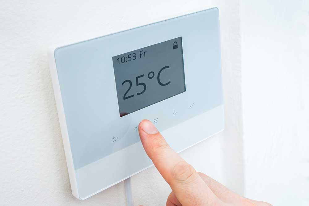 person touching wall mounted heating control