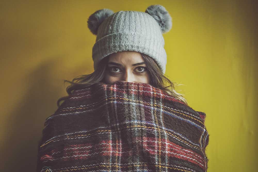 lady keeping warm in a blanket and wooly hat